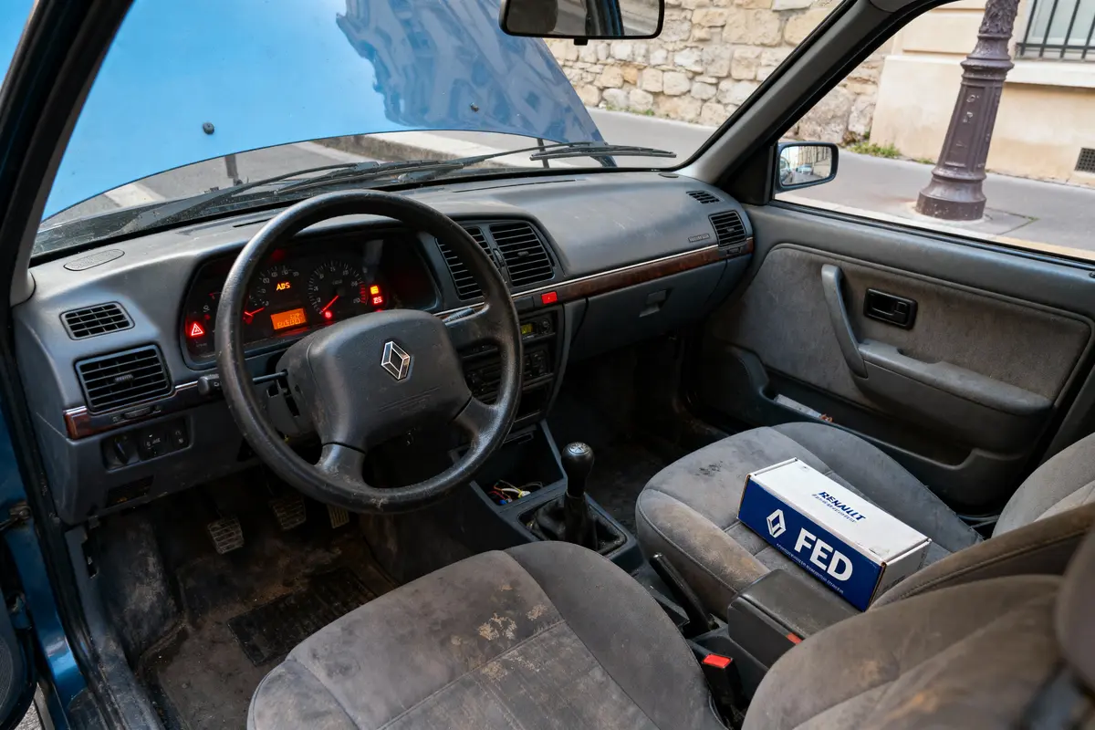 pexels-michal-pech-213601-757318 (1) Vieille voiture avec capot ouvert, volant Renault, boîte FED sur le siège passager avant, intérieur usé.