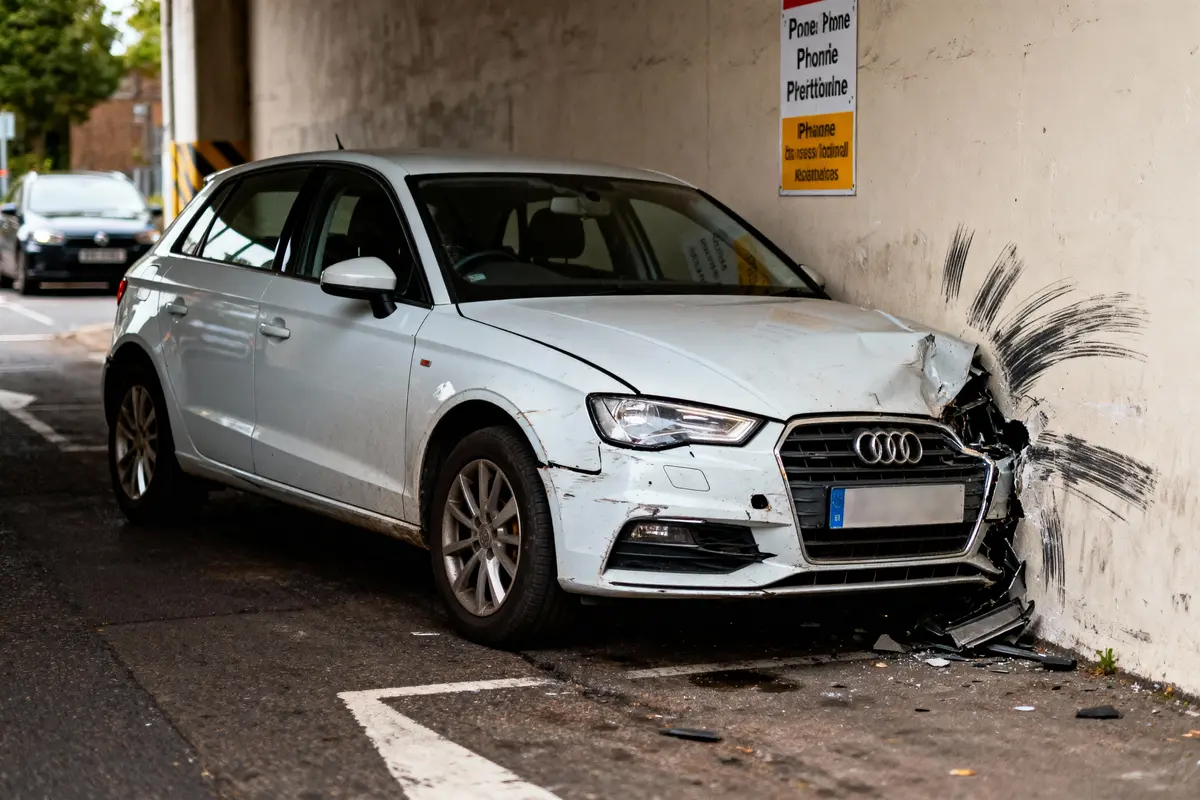 pexels-michal-pech-213601-757318 (1) Voiture blanche accidentée, écrasée contre un mur avec dégâts visibles sur le côté avant droit.