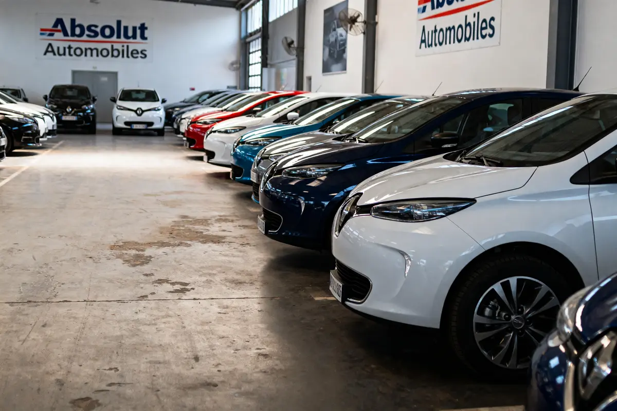 Rangée de voitures Renault électriques colorées dans un showroom "Absolut Automobiles", éclairage intérieur lumineux.