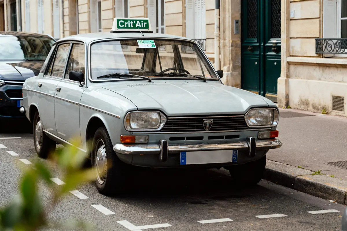 pexels-michal-pech-213601-757318 (1) Voiture ancienne grise stationnée, rue urbaine, Crit'Air sur le toit, bâtiments historiques en arrière-plan.