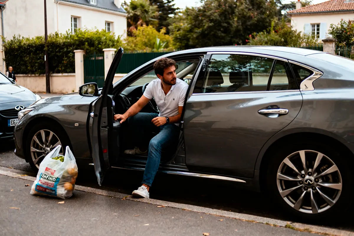 pexels-michal-pech-213601-757318 (1) Un homme sort d'une voiture grise, portant un sac de courses posé au sol.