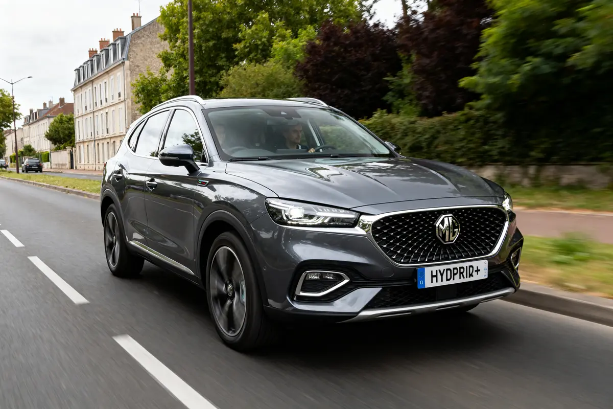 pexels-michal-pech-213601-757318 (1) SUV MG EHS gris roulant en ville sur une route bordée d'arbres et bâtiments