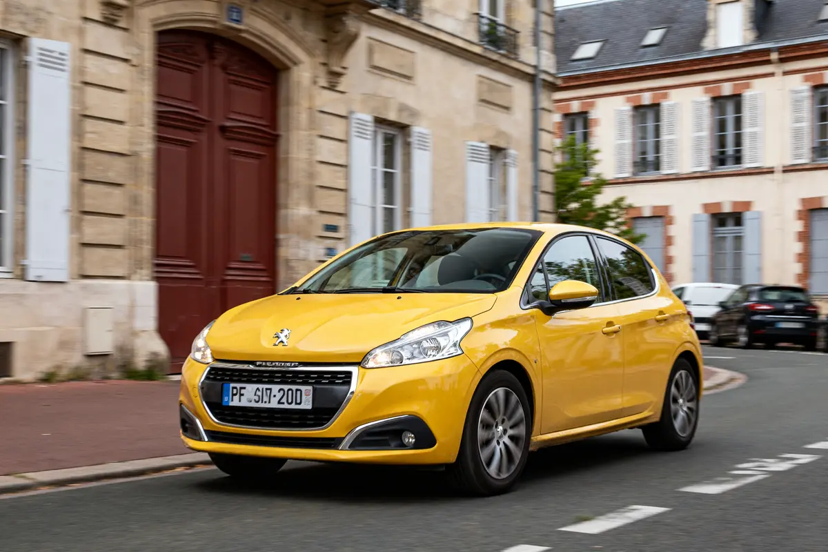 pexels-michal-pech-213601-757318 (1) Voiture 208 jaune circulant dans une rue de ville avec bâtiments historiques adjacents