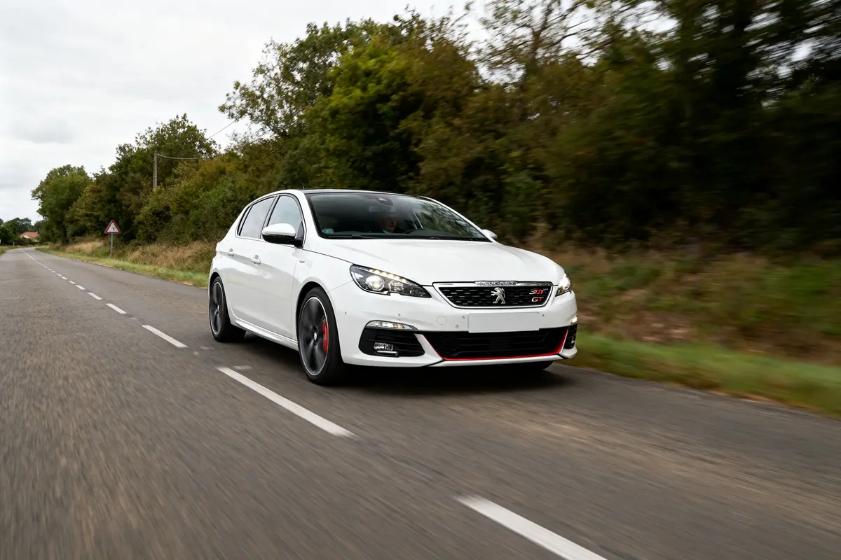 pexels-michal-pech-213601-757318 (1) Voiture blanche 308 GTi roule sur route bordée d'arbres en pleine nature