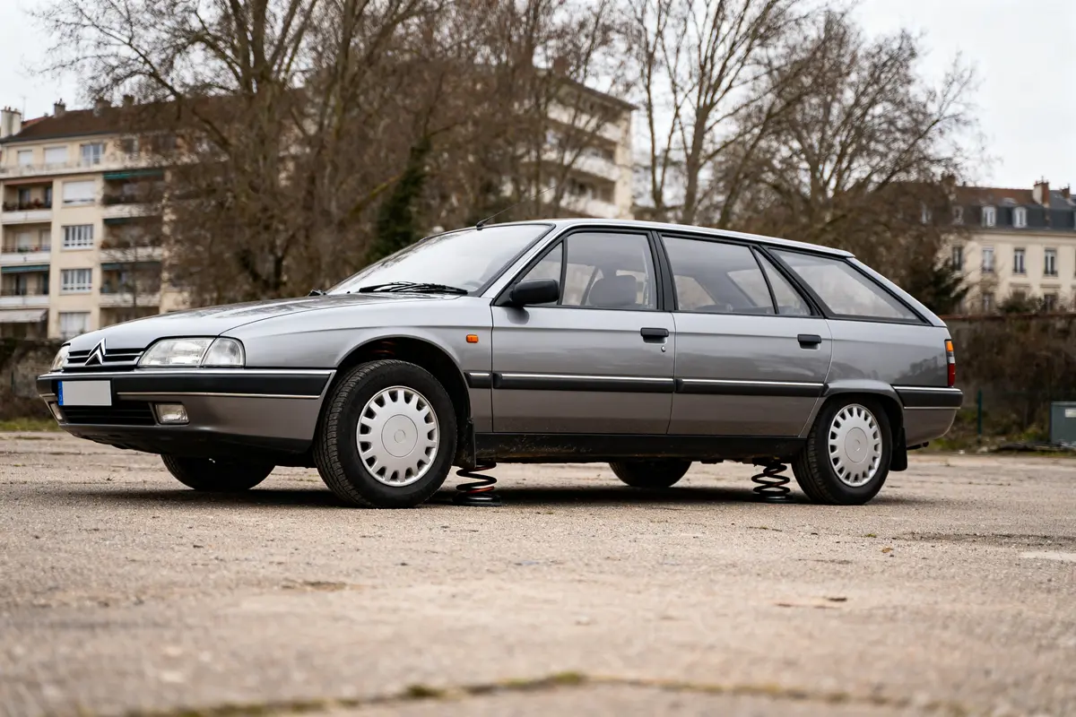 pexels-michal-pech-213601-757318 (1) Citroën XM Estate gris garée sur un parking urbain arbre et immeubles en arrière-plan