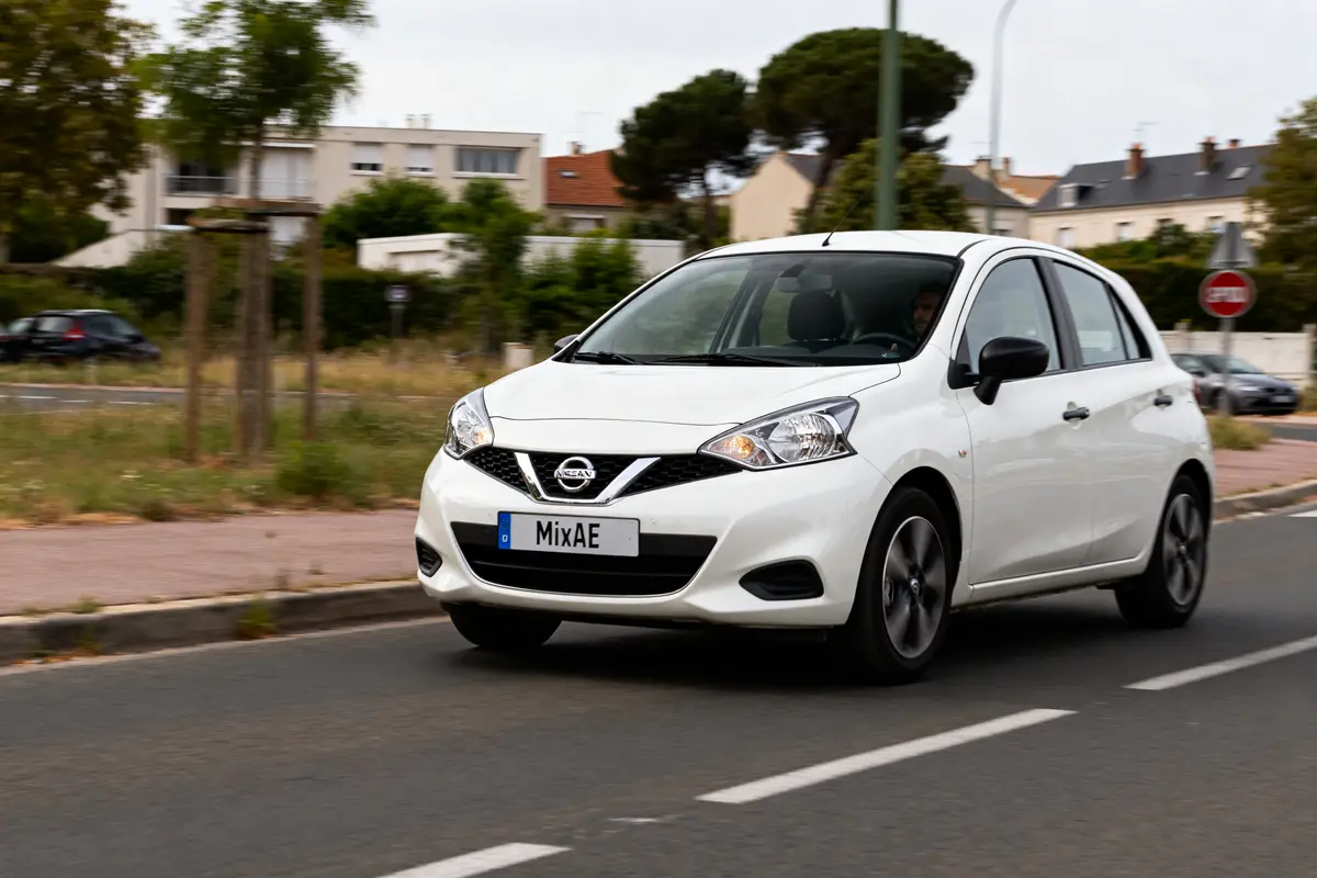 pexels-michal-pech-213601-757318 (1) Voiture Nissan Micra blanche roulant en ville avec immeubles en arrière-plan