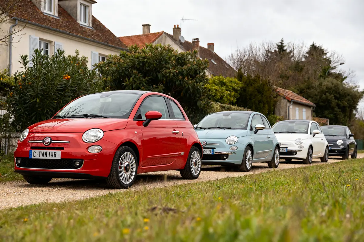 Plusieurs modèles de Fiat 500 à éviter garés devant des maisons dans une rue calme