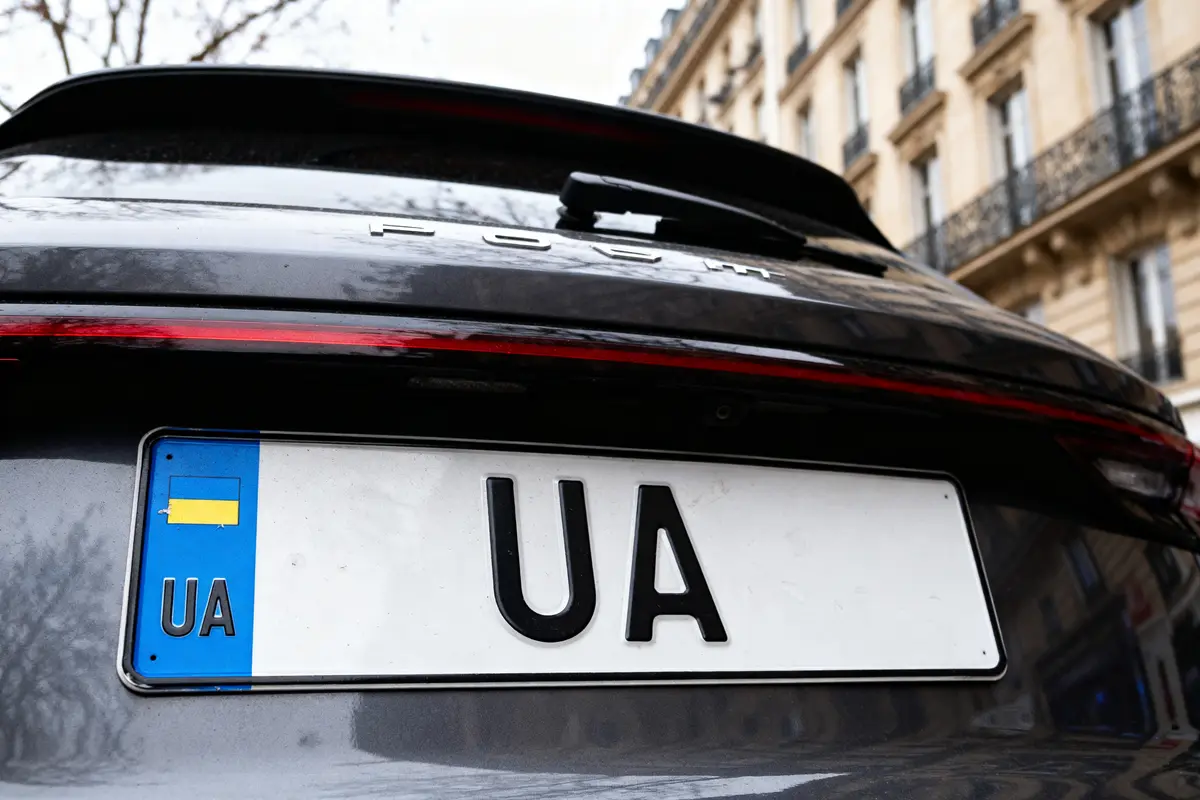 Plaque d'immatriculation UA sur voiture noire devant immeuble parisien élégant