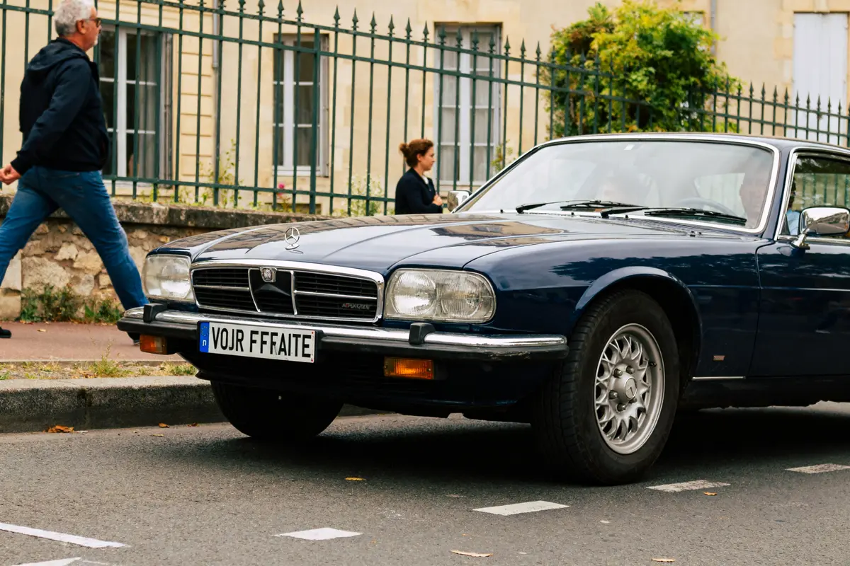 pexels-michal-pech-213601-757318 (1) Voiture Frégate ancienne bleue garée dans la rue avec passants et bâtiment en arrière-plan